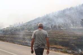 Άτομο μπροστά από καμένες εκτάσεις