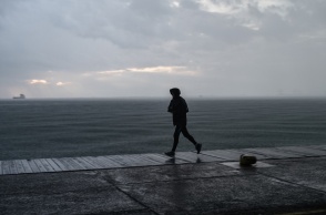 Πολίτης με αδιάβροχο τρέχει στην παραλία της Θεσσαλονίκης