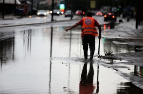 Πλημμυρισμένο σημείο της οδού Πειραιώς και άτομο που επιχειρεί να ανοίξει φρεάτια
