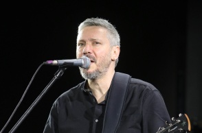 Ο Αλκίνοος Ιωαννίδης μπροστά στο μικρόφωνο με την κιθάρα στο χέρι