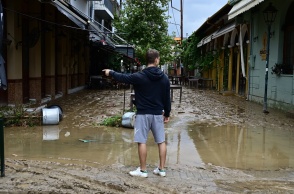 Άνδρας γυρισμένος πλάτη στον φωτογραφικό φακό περπατά σε λάσπες σε δρόμο στο κέντρο της πόλης του Βόλου μετά την κακοκαιρία Daniel