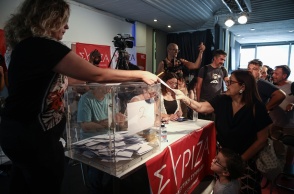 Γυναίκα με το παιδί της προσέρχονται στην κάλπη για τις εσωκομματικές εκλογές ανάδειξης νέου προέδρου στον ΣΥΡΙΖΑ