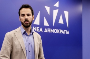 Ο Νίκος Ρωμανός μπροστά από το λογότυπο της Νέας Δημοκρατίας 