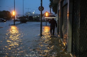 Άνδρας περπατά σε πλημμυρισμένο δρόμο στον Βόλο