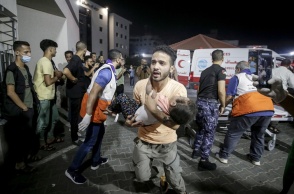 Άνδρας μεταφέρει ένα παιδί στα χέρια του στο νοσοκομείο στη Γάζα