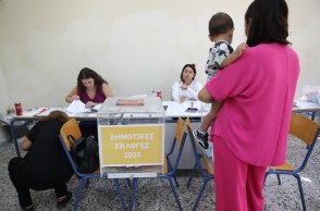 Γυναίκα κρατά το παιδί της στην αγκαλιά και προσέρχεται στην κάλπη για τις Αυτοδιοικητικές Εκλογές 2023
