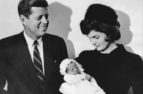 Η Τζον Φ. Κένεντι και η σύζυγός του Τζάκι, φωτογραφίζονται κρατώντας το νεογέννητο μωρό τους