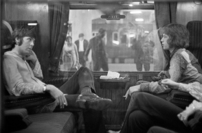 Ο Paul McCartney των Beatles και ο Mick Jagger των Rolling Stones κάθονται ο ένας απέναντι από τον άλλο σε ένα τρένο στο σταθμό Euston, περιμένοντας την αναχώρηση για το Bangor,
