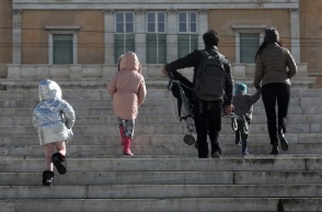 Πολίτες με παιδιά και με χοντρά ρούχα και σκουφιά για το κρύο ανεβαίνουν τα σκαλιά στην πλατεία Συντάγματος