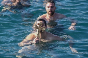 Νεαρός κρατά τον Σταυρό που μόλις έχει πιάσει από τα παγωμένα νερά της θάλασσας