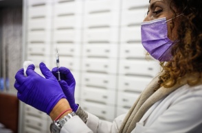 Γυναίκα κρατά εμβόλιο και βαμβάκι στα χέρια της