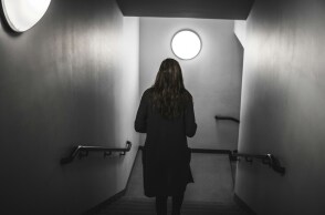 Γυναίκα με γυρισμένη πλάτη σε σκοτεινό διάδρομο