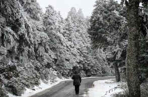 Άτομο με χοντρά ρούχα και κουκούλα περπατά στο χιονισμένο τοπίο