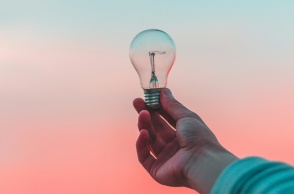 Χέρι κρατά μία λάμπα  με φόντο τον ουρανό