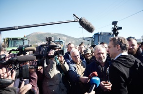 Ο Κυριάκος Μητσοτάκης κάνει δηλώσεις στα τηλεοπτικά συνεργεία ενώ στο βάθος της φωτογραφίας υπάρχουν παραταγμένα τρακτέρ