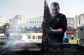 Ψήστης γυρνά τις σχάρες με τα κοψίδια σε υπαίθριο ψήσιμο την Τσικνοπέμπτη