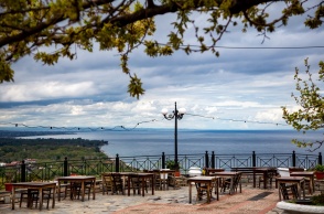 Συννεφιασμένος καιρός και υπαίθρια ταβέρνα με τραπεζάκια σε μπαλκόνι με θέα