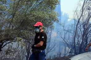 Πυροσβέστης με μάσκα για τους καπνούς κρατά τη μάνικα
