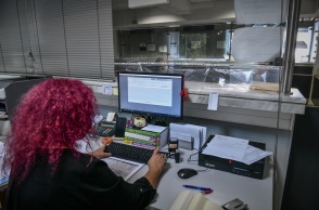 Γυναίκα με κόκκινα μαλλιά πλάτη στον φακό σε υπηρεσία συντάσσει φορολογική δήλωση στον υπολογιστή της