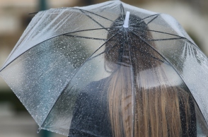 Γυναίκα κρατά ομπρέλα για να προστατευτεί από τη βροχή