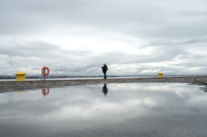 Γυναίκα στέκεται στην παραλία της Θεσσαλονίκης με συννεφιασμένο καιρό