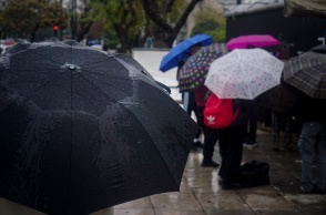 Πολίτες με ομπρέλες προστατεύονται από τη βροχή