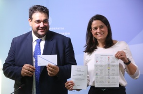 Η Νίκη Κεραμέως και ο Θοδωρής Λιβάνιος κρατούν τον φάκελο και το περιεχόμενό του για την επιστολική ψήφο