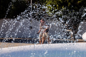 Πολίτες περπατούν πίσω από συντριβάνι