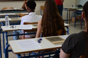 Μαθητές καθισμένοι στις καρέκλες τους μέσα στο εξεταστικό κέντρο, έχουν μπροστά τους το τετράδιο απαντήσεων των Πανελληνίων 2024