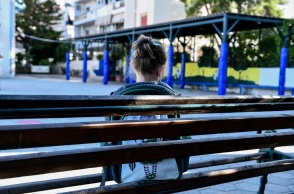 Παιδί με τη τσάντα του στην πλάτη κάθεται σε παγκάκι στο προαύλιο σχολείου