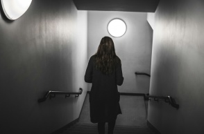 Γυναίκα περπατά σε σκοτεινό διάδρομο - Εικόνα που παραπέμπει σε κακοποίηση και ενδοοικογενειακή βία