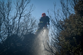 Πυροσβέστης με τη μάνικα ανά χείρας επιχειρεί για την κατάσβεσης φωτιάς