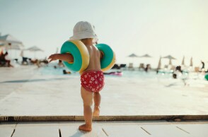 Παιδάκι με μπρατσάκια σε εξέδρα οργανωμένης παραλίας έχει την πλάτη στον φακό