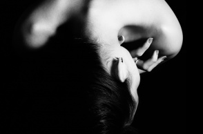 Η πλάτη και ο λαιμός γυναίκας που προστατεύει το μπροστινό μέρος του σώματός της - Μία εικόνα που παραπέμπει σε κακοποίηση