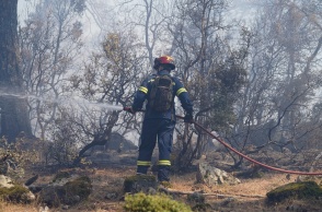 Πυροσβέστης με τη μάνικα ανά χείρας επιχειρεί για την κατάσβεσης φωτιάς