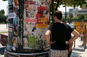 Ενοικιαστήρια σε κολώνα και νεαρό άτομο που κοιτά ενοικιαστήρια