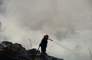 Γυναίκα πυροσβέστης επιχειρεί με τη μάνικα για την κατάσβεση φωτιάς