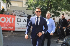 Ο Στέφανος Κασσελάκης περπατά μπροστά από πανό διαμαρτυρίας για την «Αυγή»