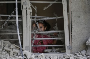 Παιδάκι πίσω από ερείπια σπιτιού στη Γάζα κοιτά τον φωτογραφικό φακό