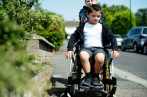 Παιδί οδηγεί το καρότσι παιδιού με κινητικές δυσκολίες