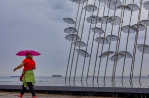 Γυναίκα κρατά ομπρέλα ενώ περπατά στην παραλία της Θεσσαλονίκης