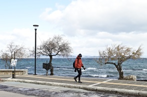 Άτομο περπατά δίπλα στη θάλασσα εν μέσω κρύου με μπουφάν και σκουφί