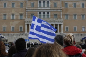 Πολίτες κρατούν ελληνική σημαία μπροστά από τη Βουλή