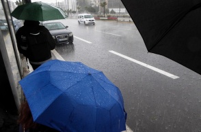 Άτομο με ομπρέλα περιμένουν εν μέσω βροχής σε στάση λεωφορείου 