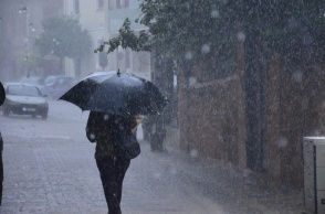 Γυναίκα προστατεύεται με ομπρέλα εν μέσω καταιγίδας