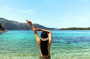 Γυναίκα τεντώνεται και απολαμβάνει τις διακοπές της με θέα τη θάλασσα