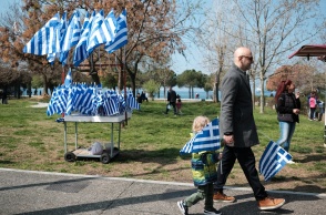 Παιδί με ελληνική σημαία και σταντ με σημαίες