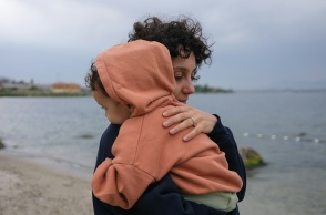 Μητέρα με παιδί αγκαλιά στην ακρογυαλιά