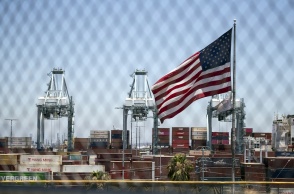 Κοντέινερ με προϊόντα και μπροστά τους η αμερικανική σημαία