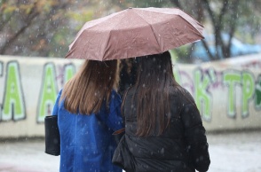 Γυναίκες προστατεύονται από τη βροχή κάτω από ομπρέλα